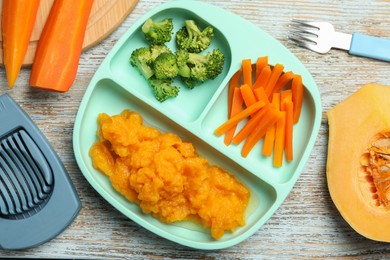 Baby food. Section plate with vegetables and pumpkin puree served on rustic wooden table, flat lay