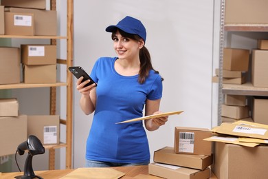 Parcel packing. Post office worker with smartphone and bag indoors