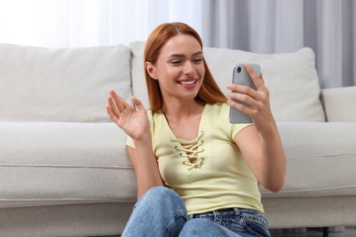 Photo of Happy young woman having video chat via smartphone at home