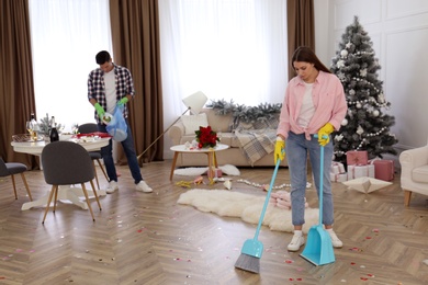 Photo of Couple cleaning messy room after New Year party