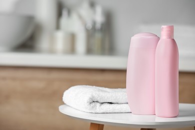 Photo of Shampoo, conditioner and towel on white table in bathroom, space for text