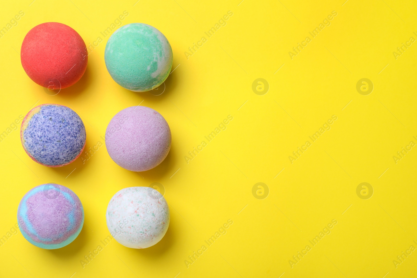 Photo of Colorful bath bombs on yellow background, flat lay. Space for text