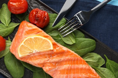 Photo of Tasty grilled salmon with tomatoes, spinach and lemon served on table, top view