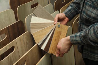 Photo of Man with samples of wooden flooring in shop, closeup