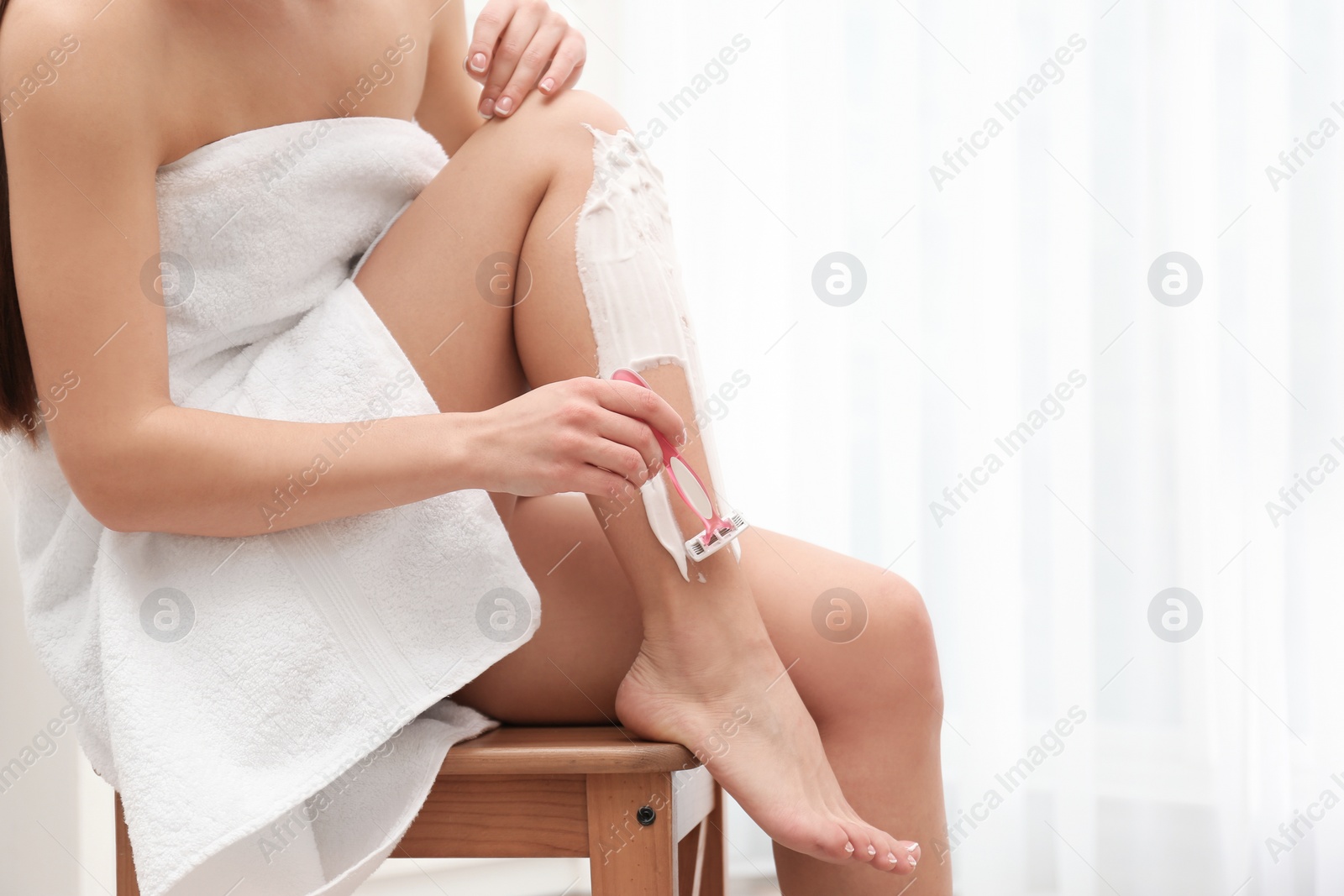 Photo of Beautiful young woman shaving leg at home. Space for text