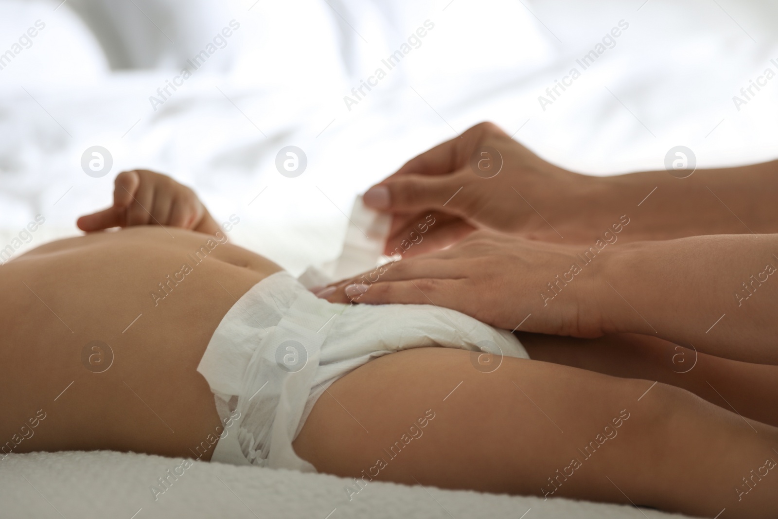 Photo of Mother changing baby's diaper on bed at home, closeup