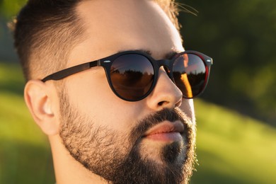 Photo of Handsome man in sunglasses outdoors, closeup. Space for text