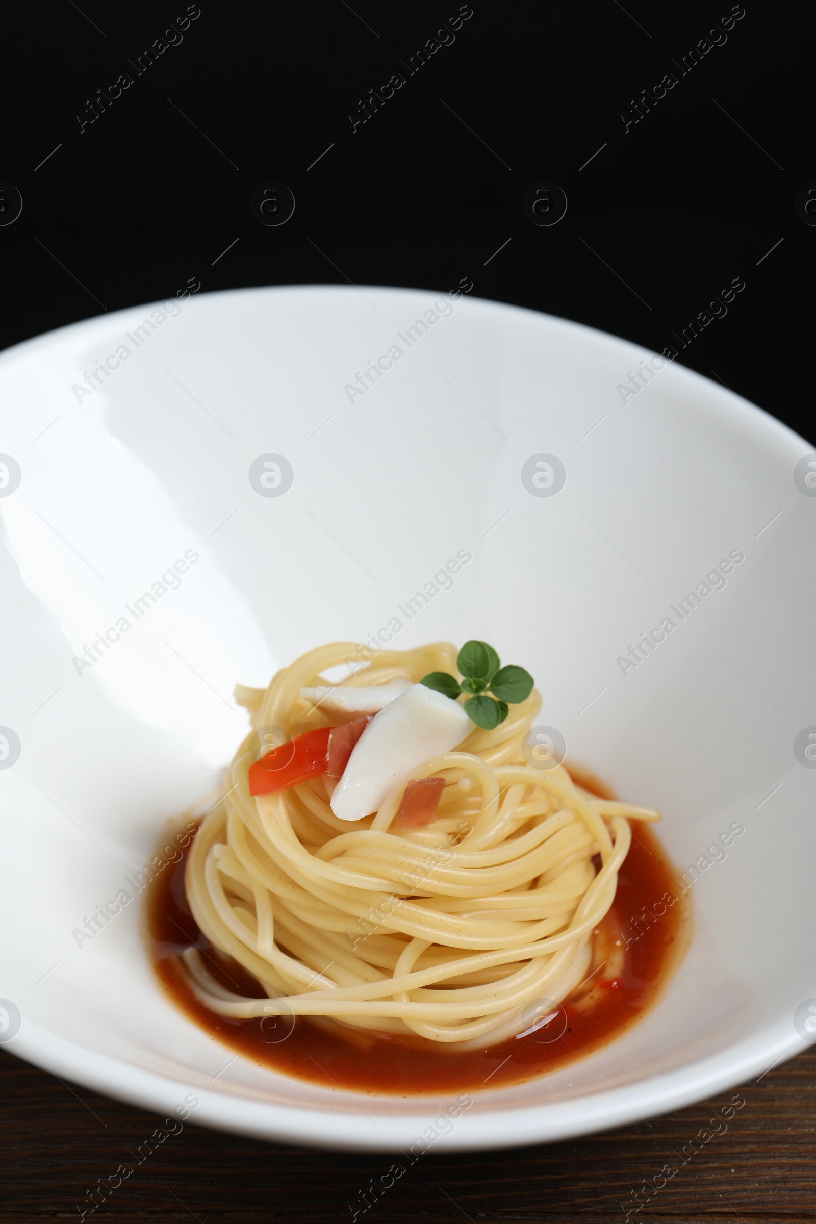 Photo of Tasty spaghetti with sauce on wooden table, closeup. Exquisite presentation of pasta dish