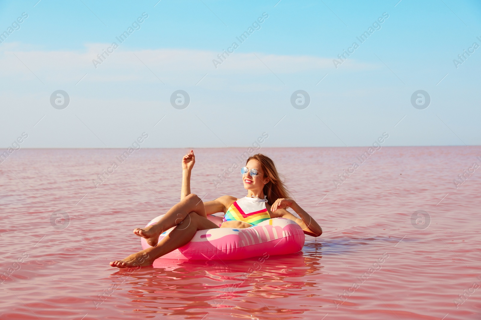 Photo of Beautiful woman on inflatable ring in pink lake