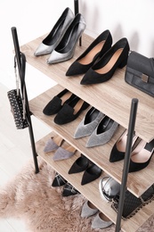 Photo of Shelving unit with stylish shoes and purses near white wall. Element of dressing room interior