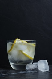 Photo of Glass of vodka with lemon slices and ice on grey table