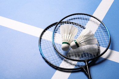 Feather badminton shuttlecocks and rackets on blue background. Space for text