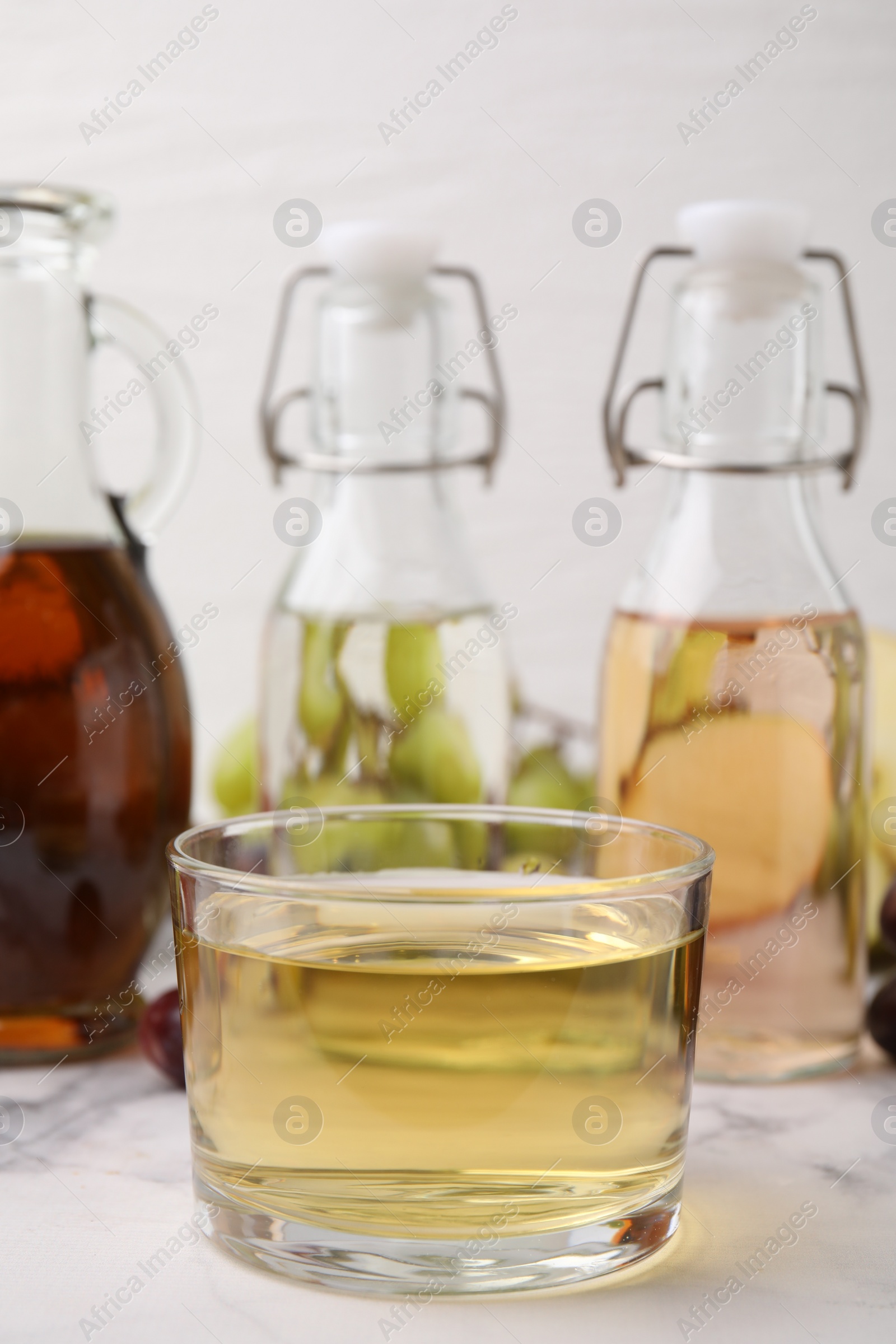 Photo of Different types of vinegar on light marble table, closeup