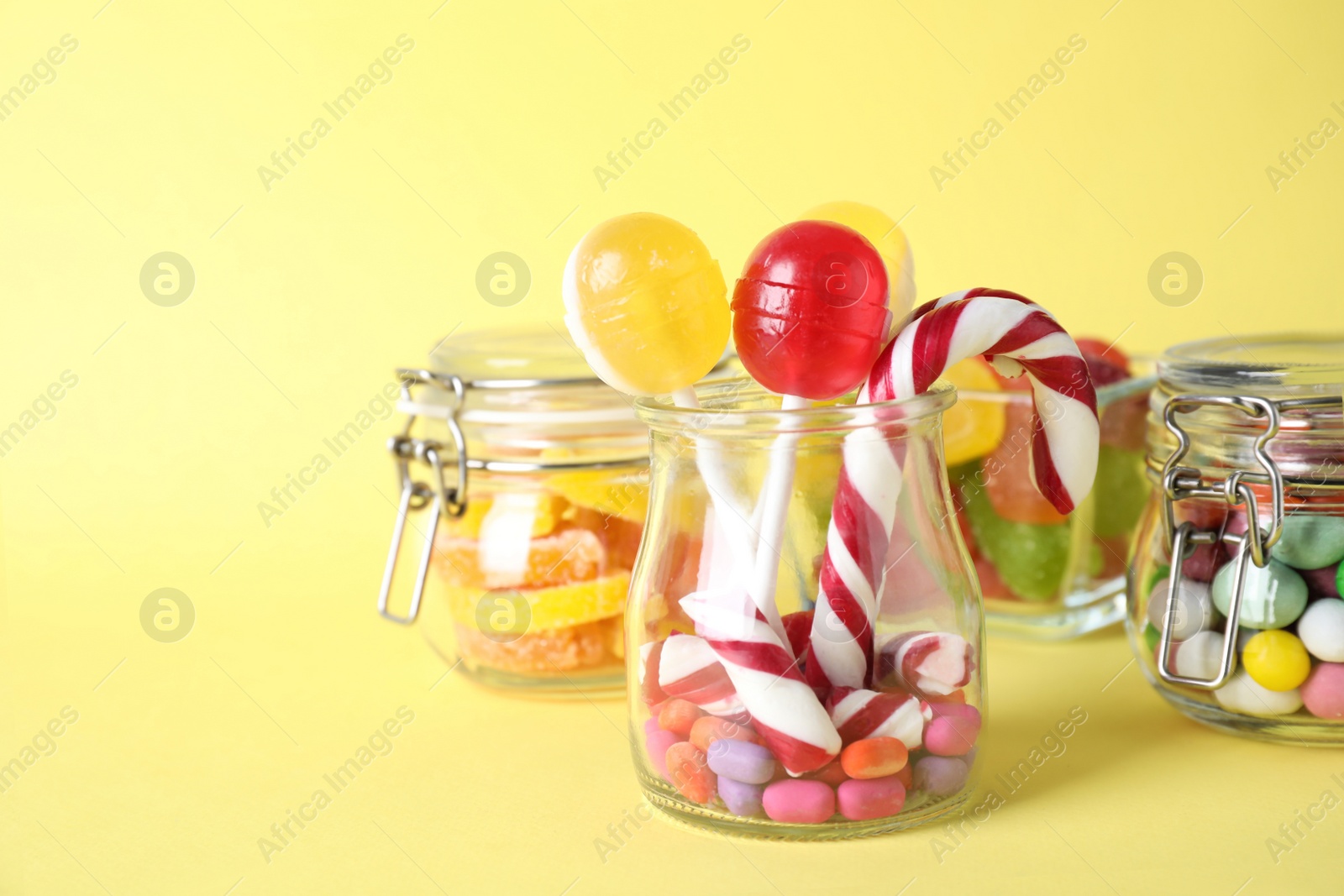 Photo of Different yummy candies on yellow background. Space for text