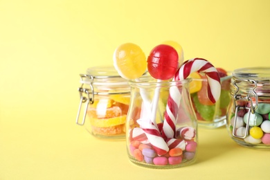 Photo of Different yummy candies on yellow background. Space for text