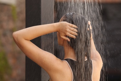 Woman washing hair in outdoor shower on summer day