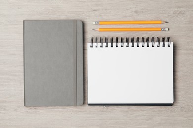 Photo of Stylish notebooks and pencils on white wooden table, flat lay