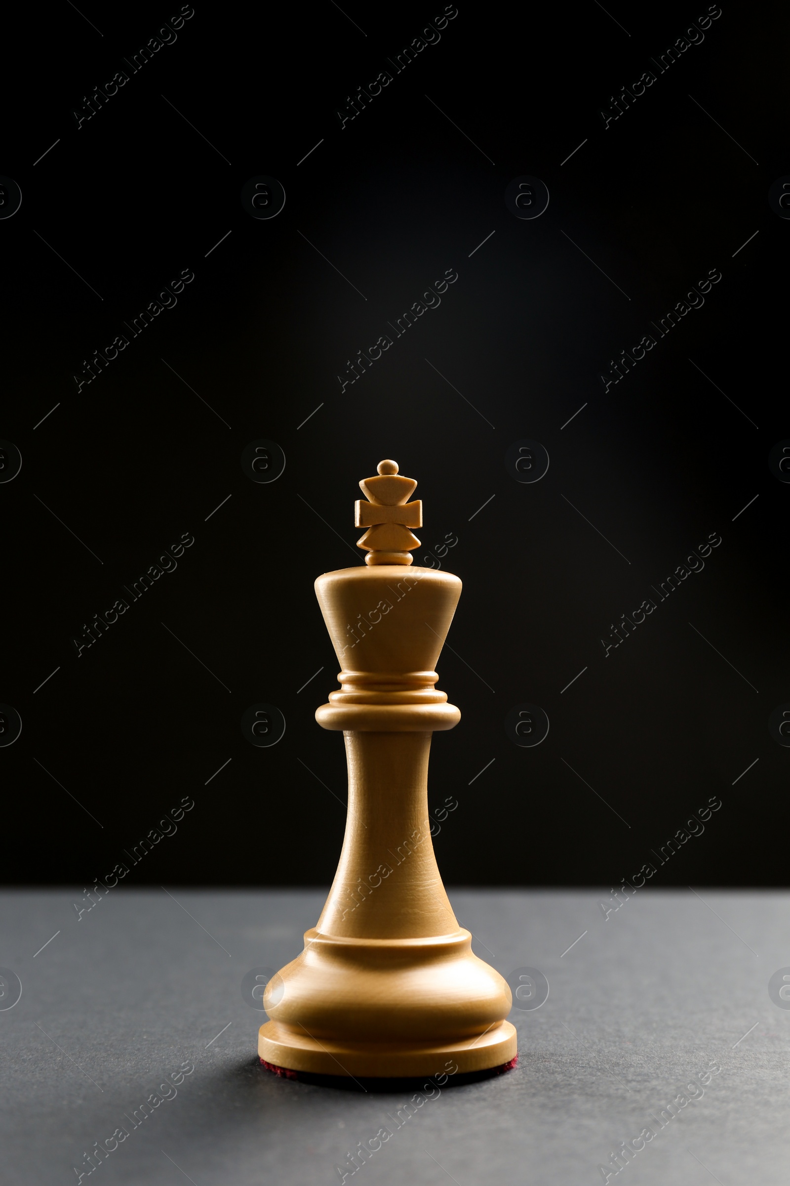 Photo of Wooden king on table against dark background, space for text. Chess piece