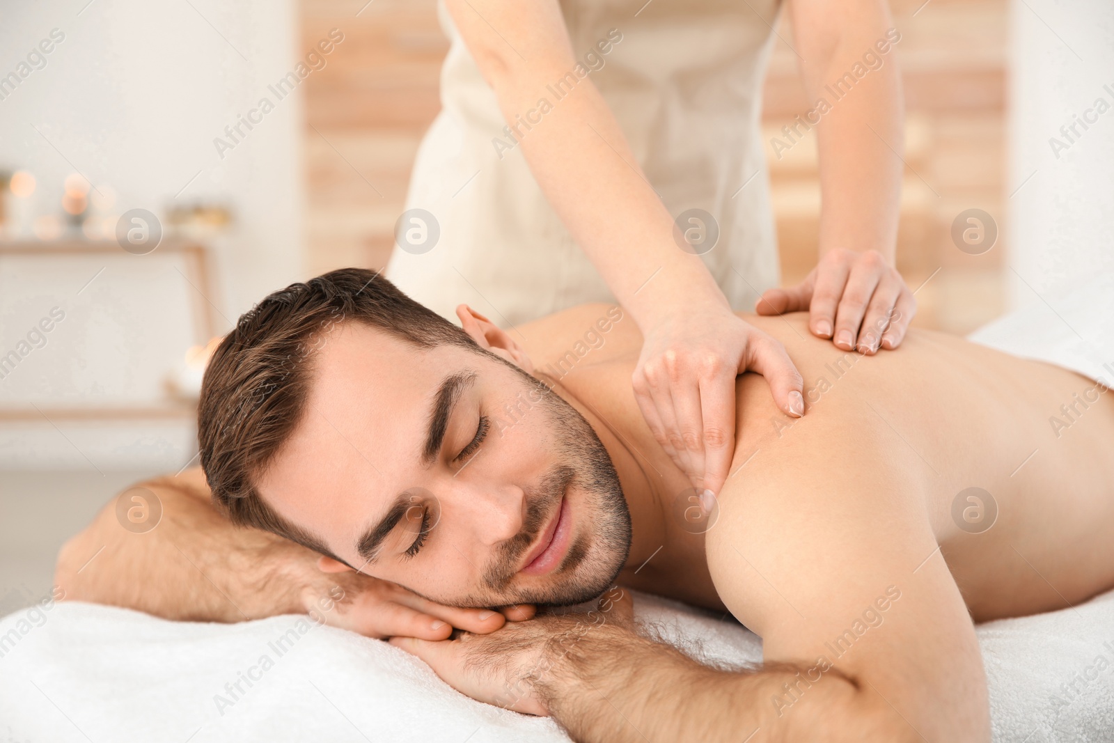 Photo of Handsome man receiving back massage in spa salon