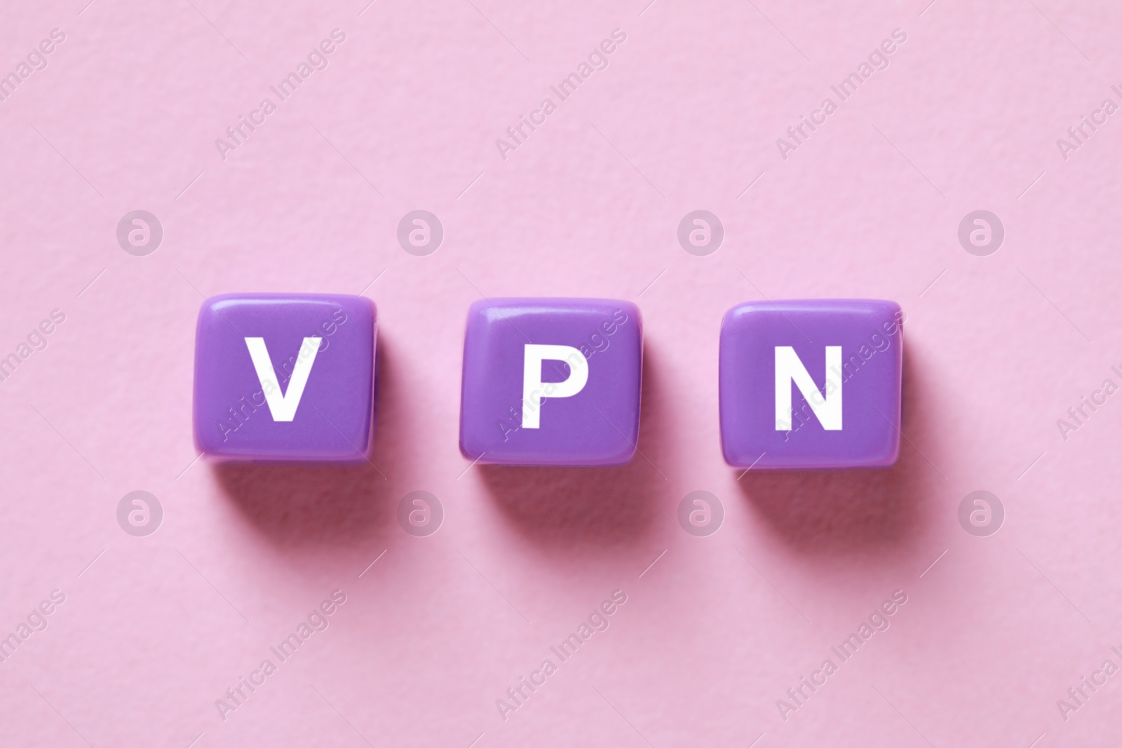 Photo of Lilac plastic beads with acronym VPN on pale pink background, flat lay