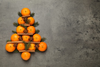 Photo of Christmas tree shape made of tangerines on grey background, flat lay. Space for text