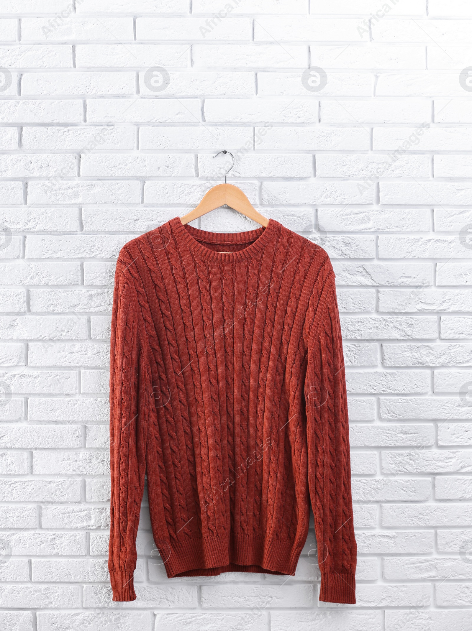 Photo of Hanger with stylish sweater on brick wall