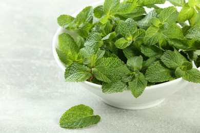 Bowl with fresh green mint leaves on grey table. Space for text