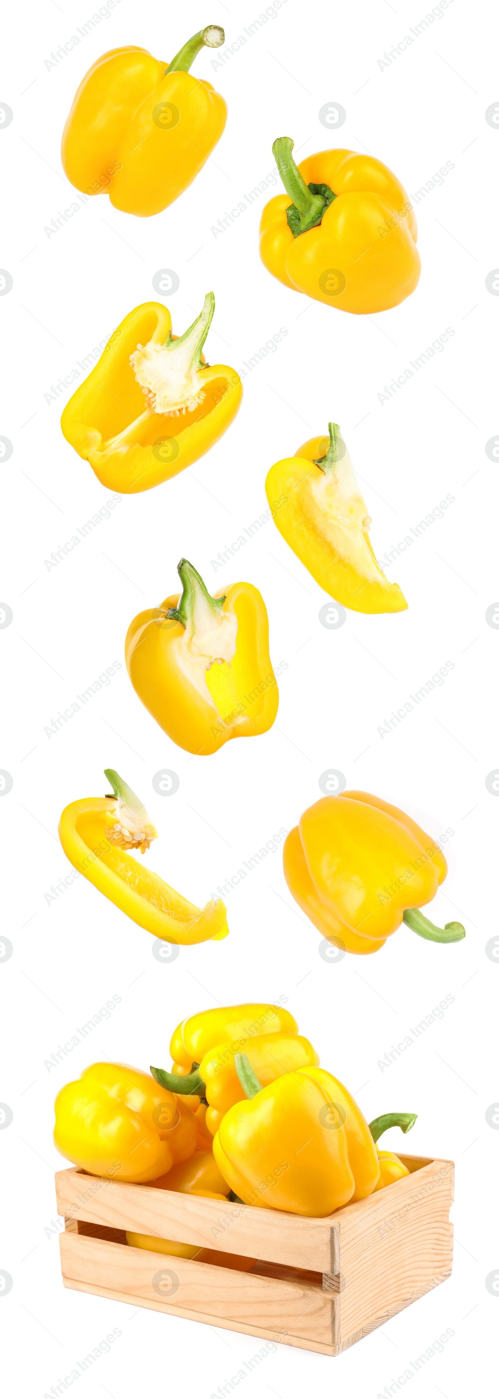 Image of Cut and whole yellow bell peppers falling into wooden crate on white background