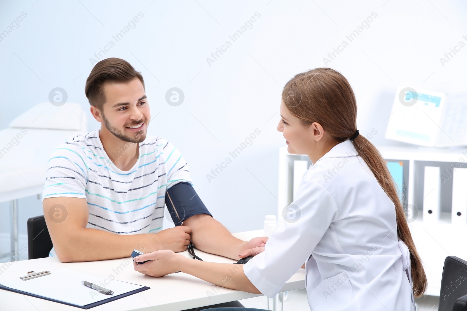 Photo of Doctor checking young man's pulse in hospital