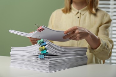 Woman stacking documents at white table in office, closeup