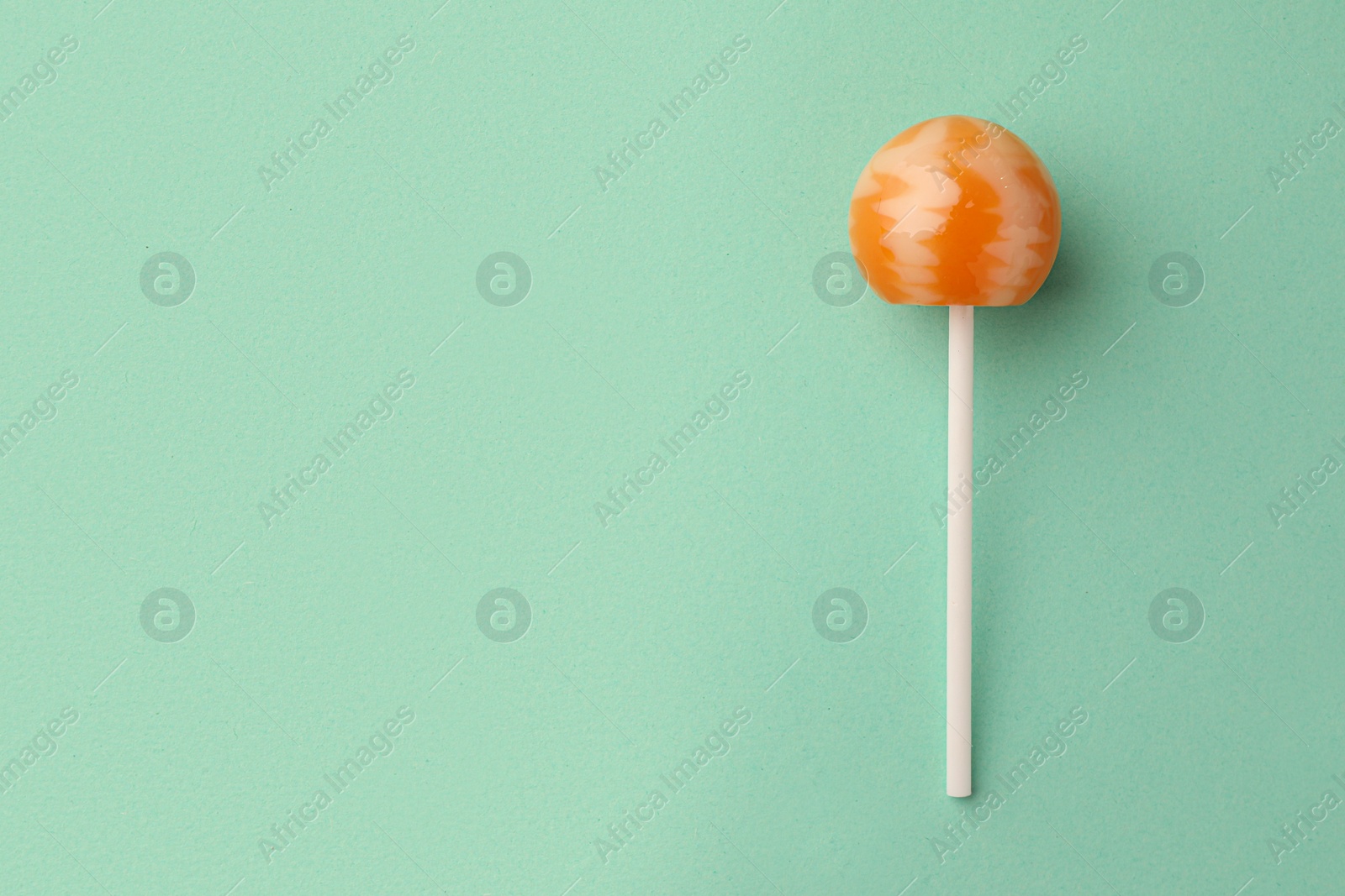 Photo of Tasty lollipop on turquoise background, top view. Space for text