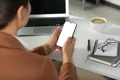 Woman using smartphone at table indoors, closeup