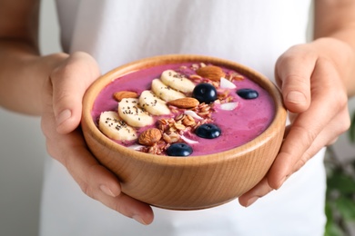 Woman holding dessert bowl with delicious acai smoothie, closeup view