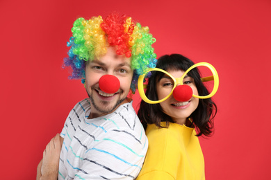 Photo of Couple with funny accessories on red background. April fool's day