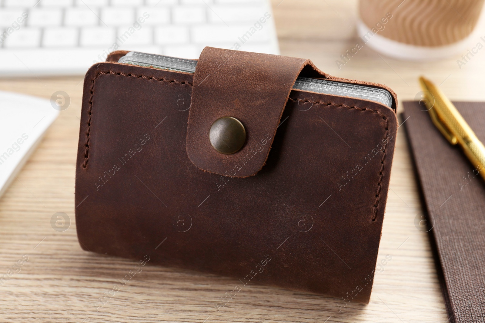 Photo of Leather business card holder and stationery on wooden table, closeup
