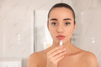 Photo of Woman with herpes applying cream on lips against blurred background. Space for text
