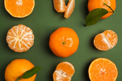 Photo of Delicious tangerines with leaves on green background, flat lay