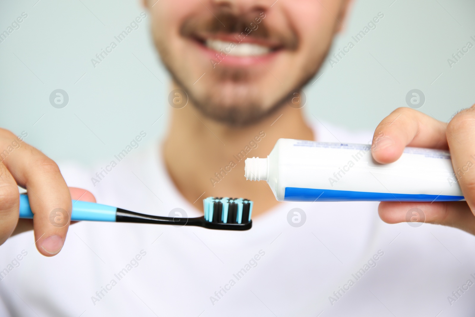 Photo of Man with toothbrush and paste on blurred background, closeup