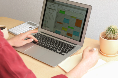 Photo of Woman using calendar app on laptop in office, closeup