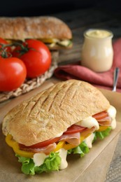 Photo of Delicious sandwich with vegetables, ham and mayonnaise served on wooden table, closeup