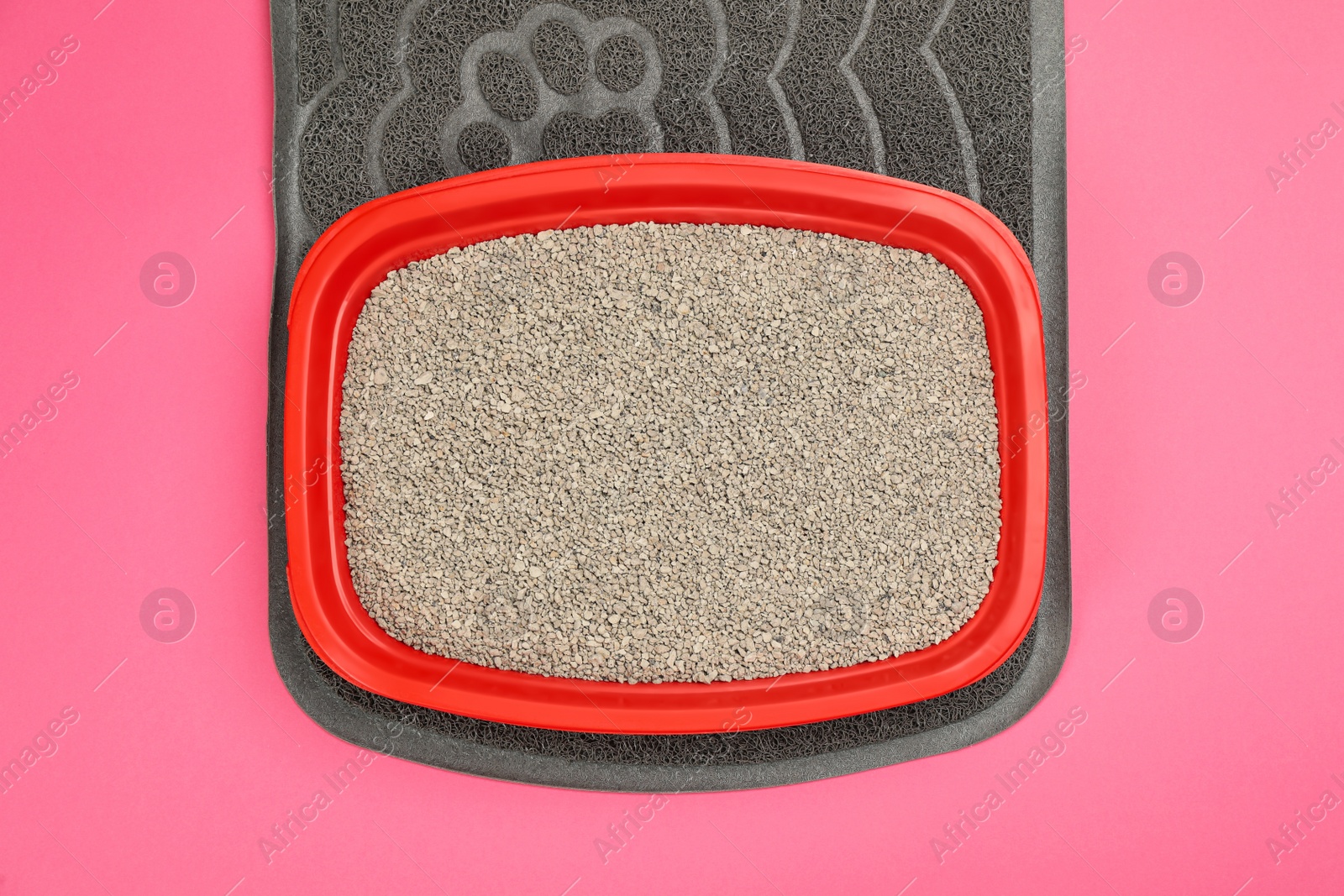 Photo of Rubber mat and cat litter tray with filler on pink background, top view