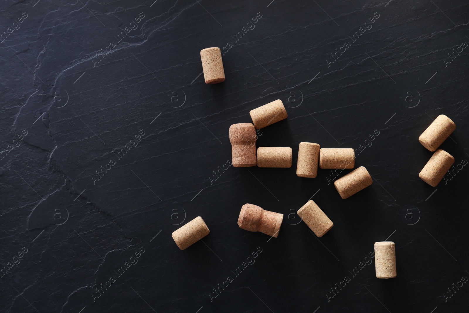 Photo of Wine bottle corks on black table, flat lay. Space for text