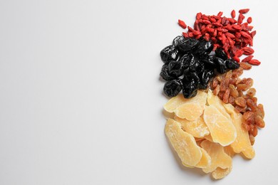 Photo of Pile of different dried fruits on white background, top view. Space for text
