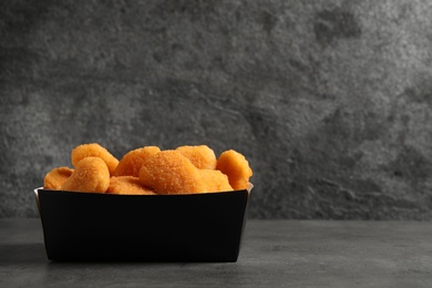 Photo of Tasty fried chicken nuggets on grey table. Space for text