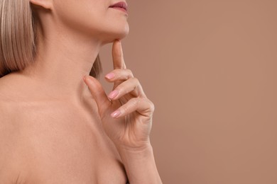 Photo of Woman touching her chin on beige background, closeup. Space for text