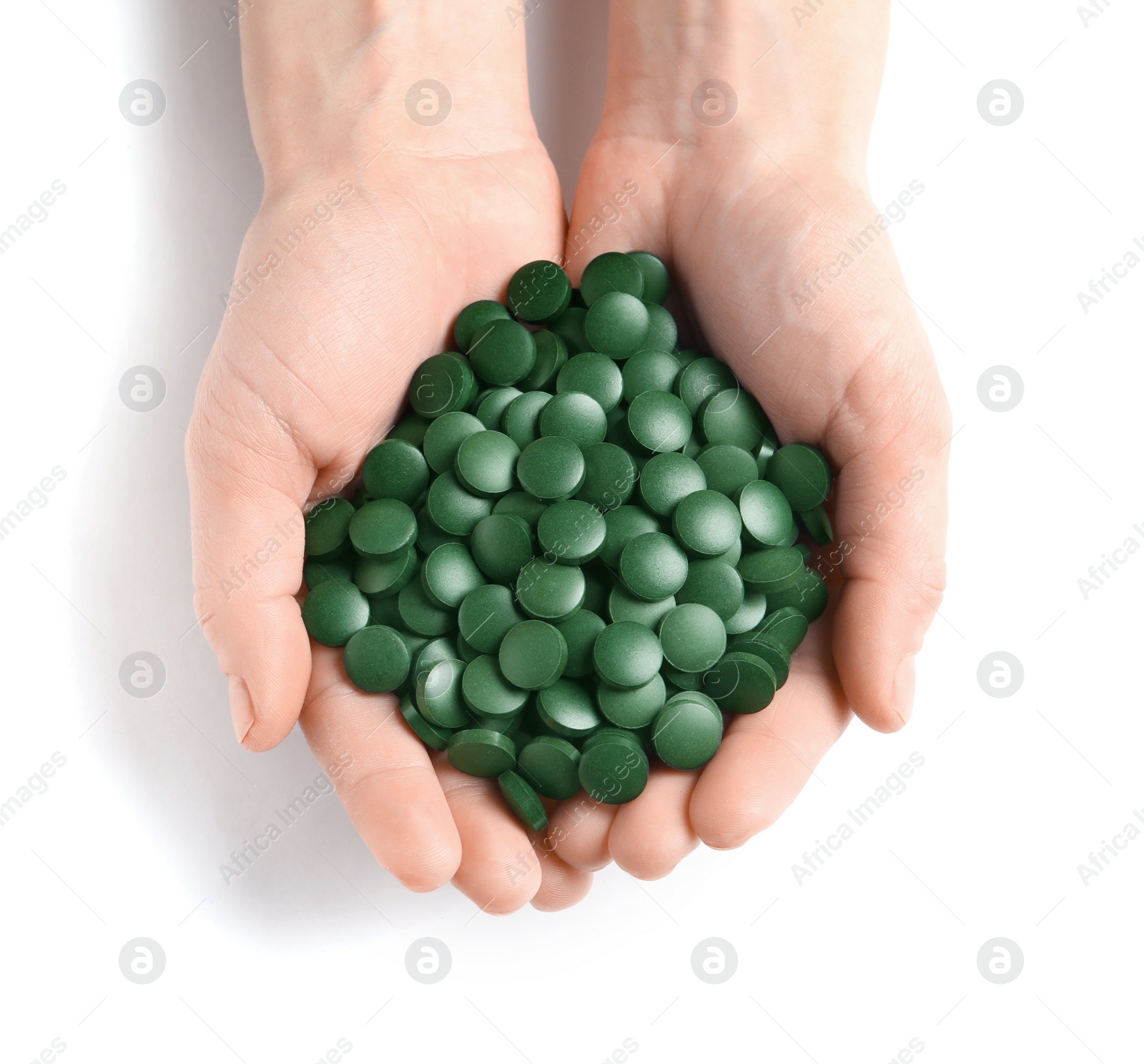 Photo of Woman holding heap of green spirulina pills on white background, top view