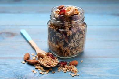 Photo of Jar of tasty granola with nuts and dry fruits on light blue wooden table