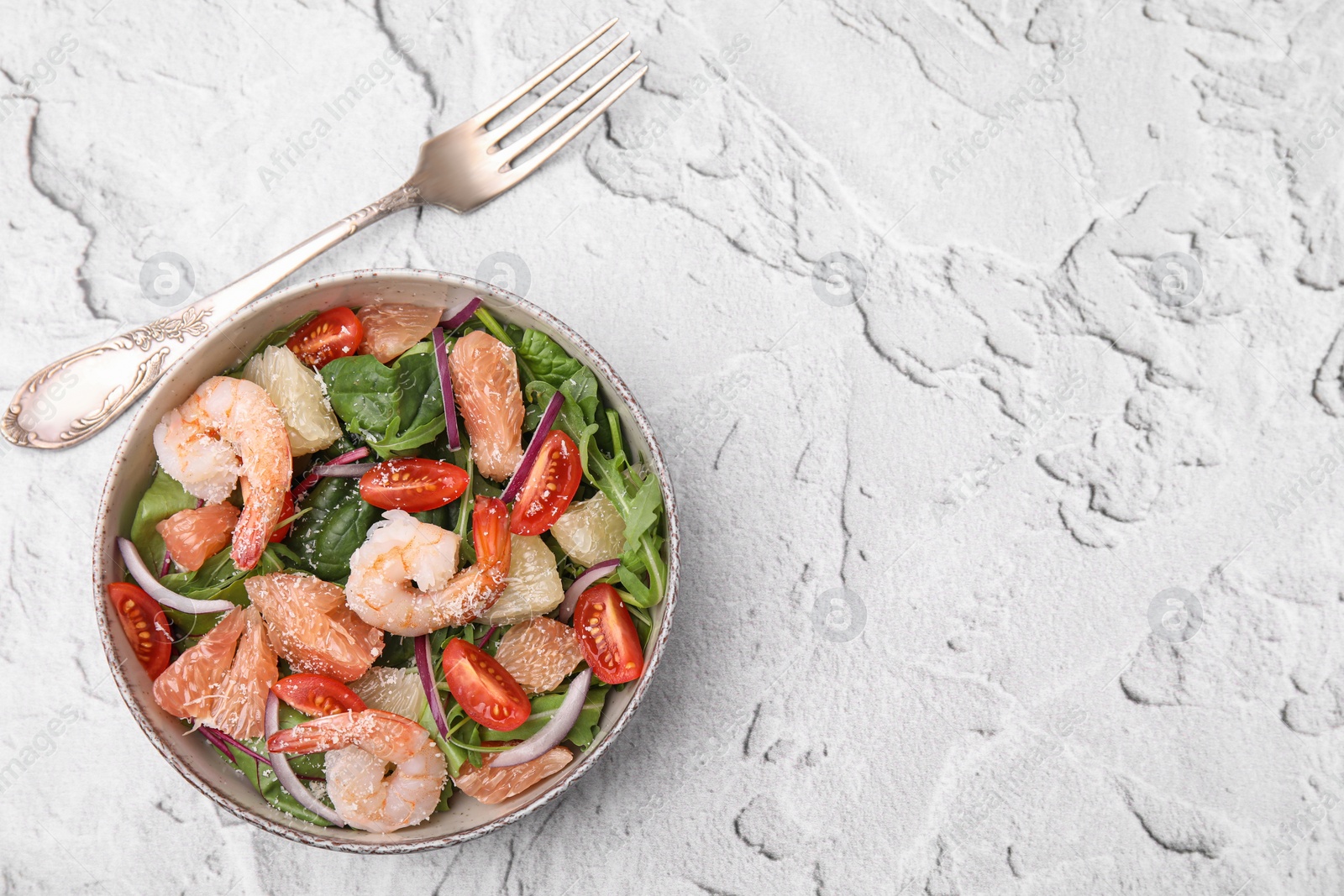 Photo of Delicious pomelo salad with shrimps served on white textured table, flat lay. Space for text
