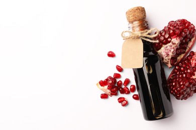 Photo of Bottle of pomegranate sauce and fresh ripe fruit on white background, top view. Space for text