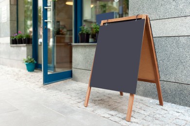 Photo of Blank advertising A-board near cafe. Mockup for design